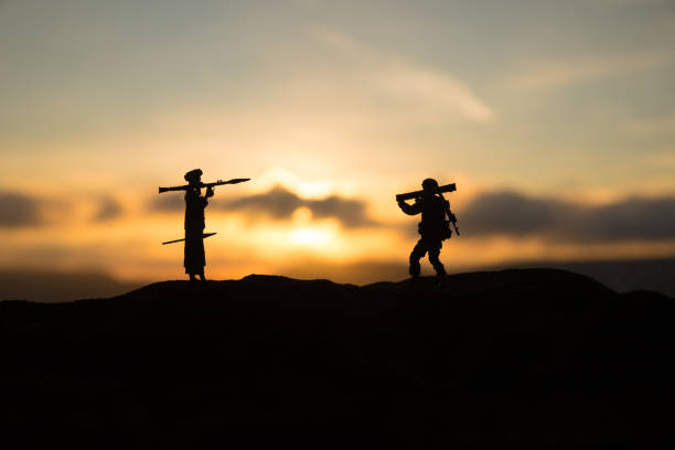 War Concept. Military silhouettes fighting scene on war fog sky background, Military soldiers silhouettes with bazooka and rpg. War Concept. Military silhouettes fighting scene on war fog sky background, Mojahed with rpg and us soldier with bazooka at sunset. Attack scene coalition photos stock pictures, royalty-free photos & images