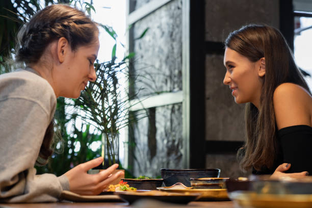 istock Two female friends chatting and having some snacks in a cafe 1221270269