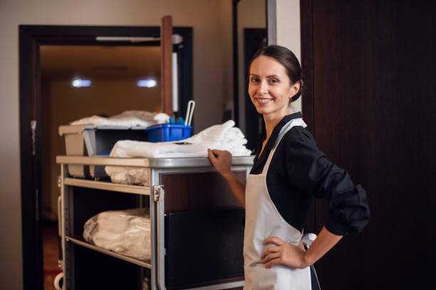 Smiling hotel maid with fresh towels doing housekeeping stock photo