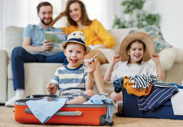 istock Playful kids in suitcases with parents on sofa behind 1221272642