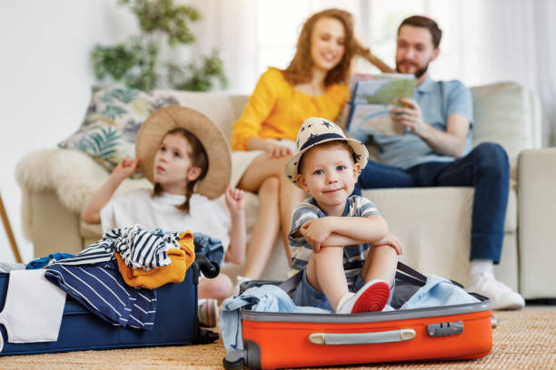 istock Playful kids in suitcases with parents on sofa behind 1221272704