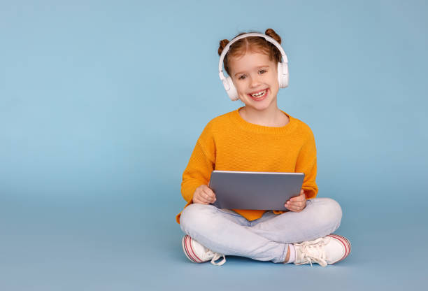 istock Cheerful girl in headphones browsing tablet 1221272761
