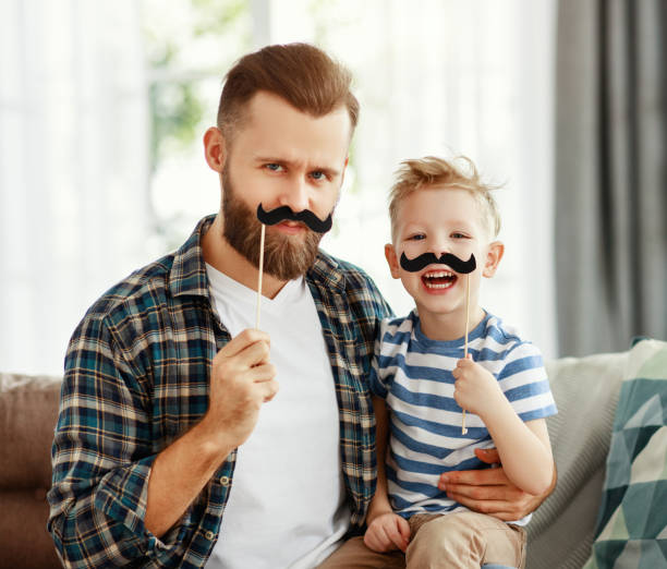 père et fils ayant l’amusement avec la moustache à la maison - fake mustache photos et images de collection