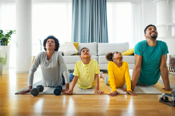 famille faisant l’exercice du yoga à la maison - être étendu sur le ventre photos et images de collection