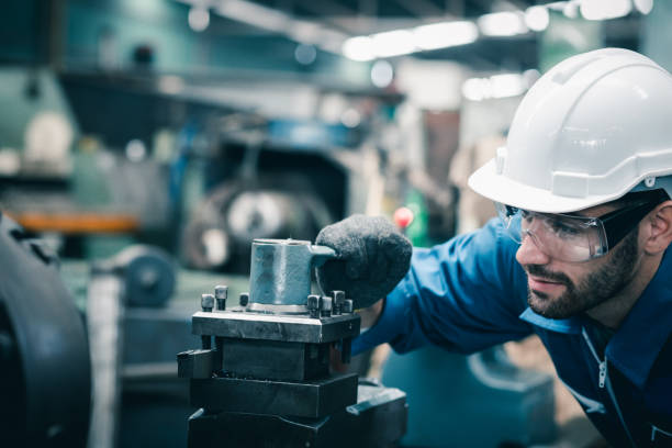 Men industrial engineer wearing a white helmet while standing in a heavy industrial factory behind. The Maintenance looking of working at industrial machinery and check security setup in factory. Men industrial engineer wearing a white helmet while standing in a heavy industrial factory behind. The Maintenance looking of working at industrial machinery and check security setup in factory. Furnace stock pictures, royalty-free photos & images