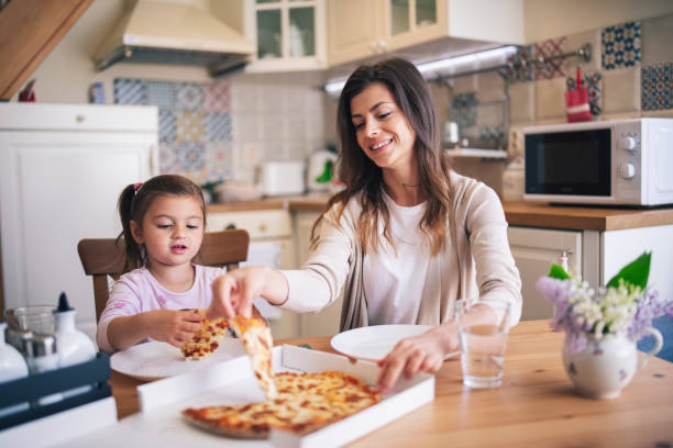 istock Mother And Daughter Eating Pizza At Home. 1221277785