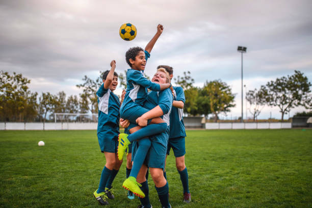 Blue Jersey Boy Footballers Cheering and Celebrating Happy teenage boy footballers wearing blue jerseys cheering and embracing on sports field. drive ball sports photos stock pictures, royalty-free photos & images
