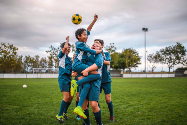 Blue Jersey Boy Footballers Cheering and Celebrating Happy teenage boy footballers wearing blue jerseys cheering and embracing on sports field. football team stock pictures, royalty-free photos & images