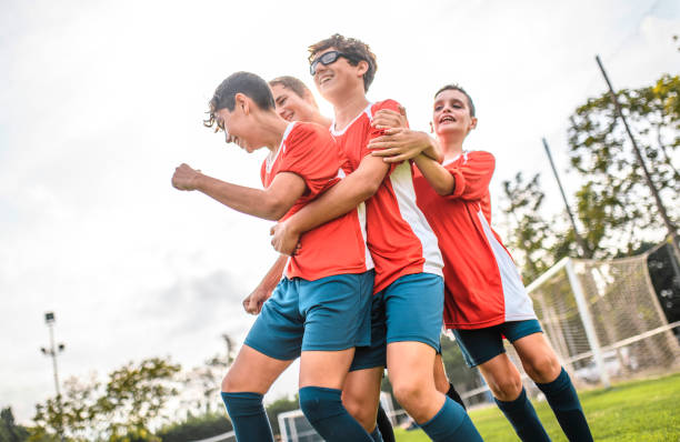 istock Red Jersey Boy Footballers Hugging Scoring Teammate 1221278028