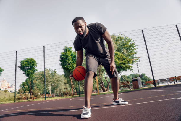 istock Outdoors Activity. African man playing on court dribbling ball between legs serious 1221278964