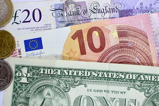 Close-up of international bank notes and coins; Pounds, Euros and Dollar.