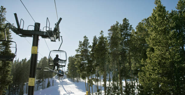 Snowboarders Ride a Ski Lift at Eldora Ski Resort near Boulder, Colorado on a Bright, Clear, Sunny Day Snowboarders Ride a Ski Lift at Eldora Ski Resort near Boulder, Colorado on a Bright, Clear, Sunny Day slopestyle stock pictures, royalty-free photos & images