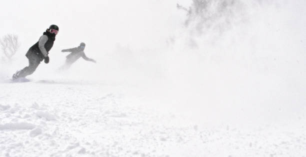 istock Several Snowboarders Boarding Down a Run and Spraying Snow at the Camera at Eldora Ski Resort near Boulder, Colorado on a Snowy, Overcast Day 1221285446