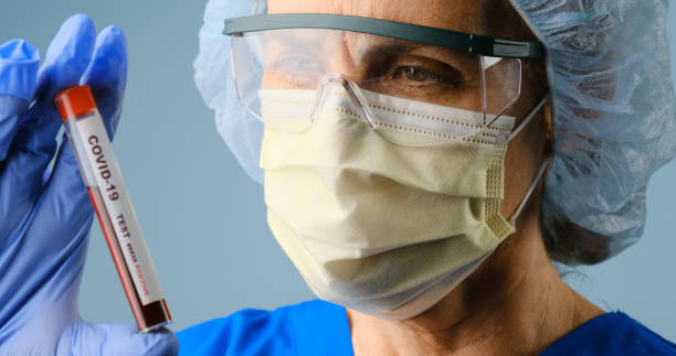 healthcare worker holding a container of covid-19 test sample - surgical glove human hand holding capsule imagens e fotografias de stock