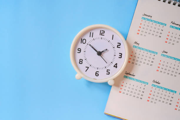 istock analog white clock with calendar on blue paper background, flat lay, deadline concept 1221291899