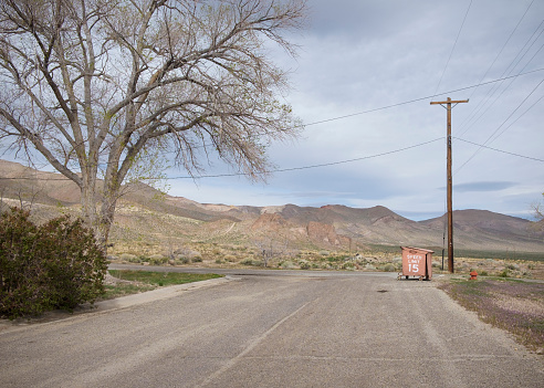 Outdoor scene with street and desert mountains, near Yerington, Nevada. Speed limit sign on dumpster.