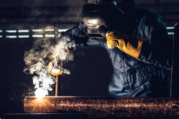 Photo of Metal welder working with arc welding machine.