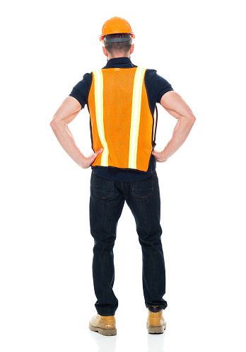 Rear view of with short hair caucasian male construction worker standing in front of white background wearing shirt who is working with hand on hip and holding hammer