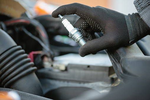 New car spark plug in auto electrician hand close up.