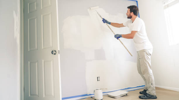 homme de peintre peignant le mur dans la maison, avec le rouleau de peinture et la peinture blanche de couleur. rénovation de la chambre à la maison. - painting wall paint paint roller photos et images de collection