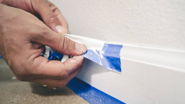 removendo fita adesiva da moldagem. um pintor tira a fita do pintor azul da parede para revelar uma tábua de base limpa. - protective varnish - fotografias e filmes do acervo