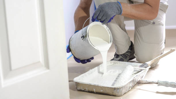 Man pours paint into the tray and dips roller. Professional interior construction worker pouring white color paint to tray. Man pours paint into the tray and dips roller. Professional interior construction worker pouring white color paint to tray. painting stock pictures, royalty-free photos & images