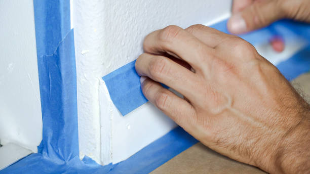 istock Painter Man Using Masking Blue Tape to Secure Baseboard, Moulding. Preparation For Room Painting. 1221308509