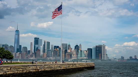 New York, USA - June 7, 2019:   American flag on Liberty Island in New York Harbor and Manhattan skyline