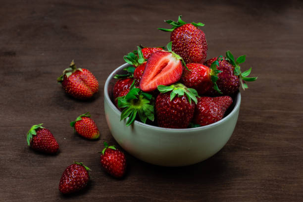 istock Fresh strawberries in ceramic bowl on dark wooden background. Selective focus. - Image 1221309300