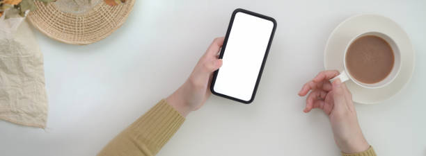 istock Top view of female freelancer using blank screen smartphone and drinking morning coffee 1221310628