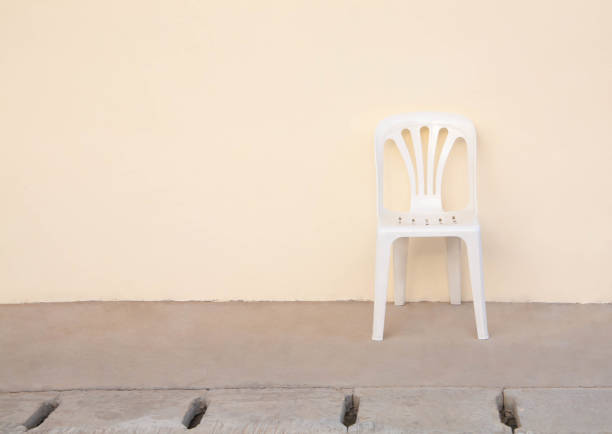 istock Single white plastic chair with old cream tone wall and grunge floor. 1221311429