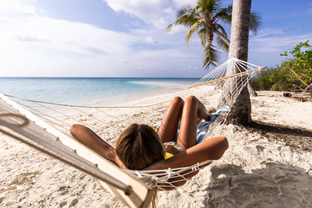istock Relaxed woman spending a summer day in hammock on the beach. 1221313617