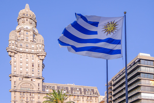 Flag of Uruguay as a symbol for patriotism at Plaza Independencia Square with Palacio Salvo palace in background, Montevideo, Uruguay, South America