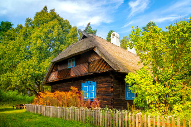 Olsztynek, Poland - August 31,2019: Old rural log house with thatched roof with a garden, Warmian-Masurian Voivodeship, Poland