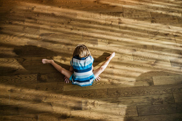 istock Above view of a small boy stretching on parquet floor. 1221316313