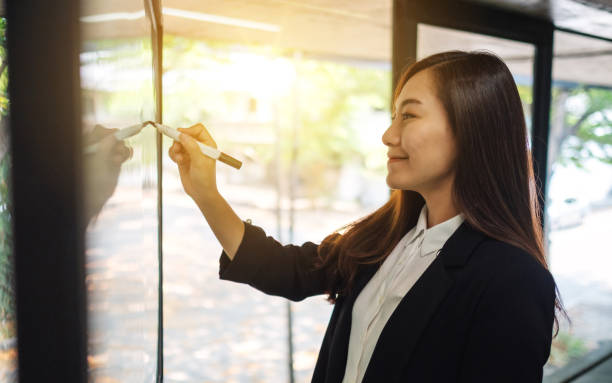 istock Businesswoman or a teacher writing on a whiteboard 1221316534