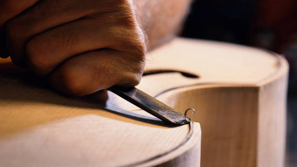 der professionelle geigenmeister macht eine geige mit seinen eigenen händen, verwendet eine reine fichte, kiefer, macht muster aus einem meißel, ebene - making craftsperson italian music musical instrument stock-fotos und bilder