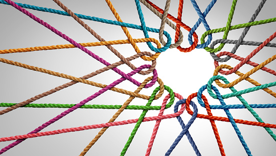 Unity and love partnership as ropes shaped as a heart in a group of diverse strings connected together shaped as a support symbol expressing the feeling of teamwork and togetherness.