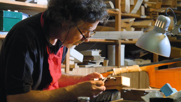 istock The professional violin master makes a violin with his own hands, uses a pure tree spruce, pine, makes patterns from a chisel, plane 1221319848