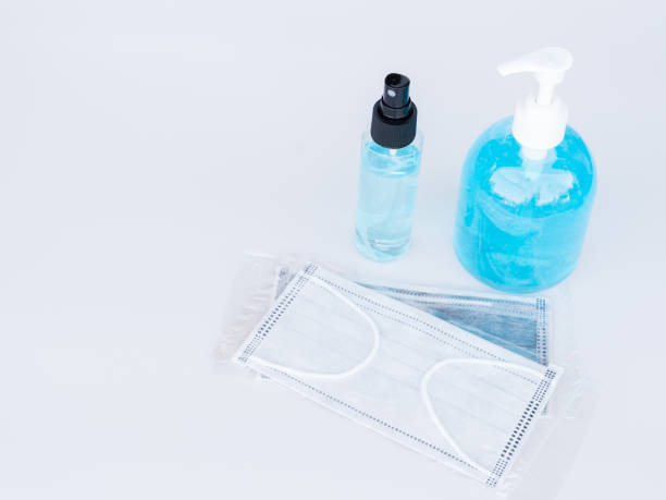 Surgical face masks in a plastic package, an alcohol spray bottle and alcohol gel bottle on white background. stock photo