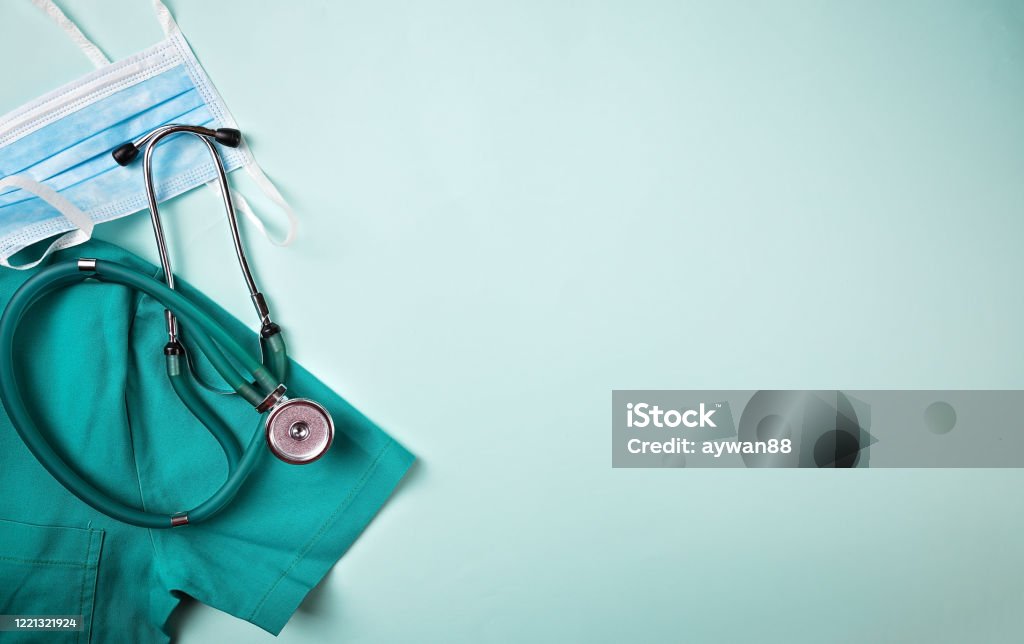 Doctor equipment flat lay background Medical flat lay background. COVID 19 healthcare medicine concept. Full frame shot of face mask placed with stethoscope and medical scrubs. All are on green background. Knolling concept. Healthcare And Medicine Stock Photo