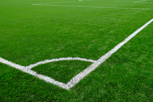white corner markings on a football field with artificial turf bright green grass
