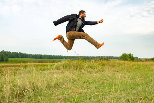 a man with a beard running high above the ground almost flies. the aspiring white man in summer runs in socks alone on the field