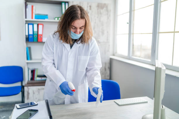istock One man in protective gloves disinfecting office work space 1221322522