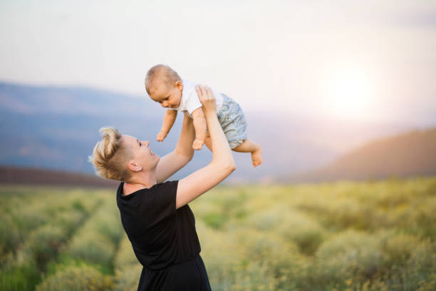 istock Beautiful woman keeps a son on her hands, raises the elevators on her son's hands in the summer. Mother and child in nature 1221322659
