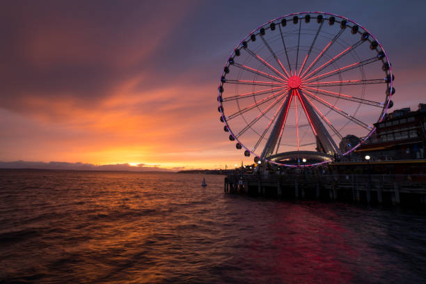 Elliott bay gold Elliott Bay sunset with the Ferris wheel illuminated to support the emergency workers on the front line of the Covid-19 pandemic. elliott bay photos stock pictures, royalty-free photos & images