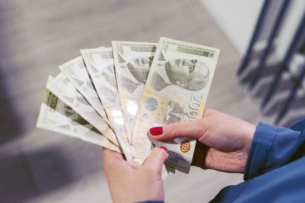 Close up on serbian dinar RSD money banknotes in hand of unknown caucasian woman holding currency after receiving payment loan or help financial aid support due to economic recession crisis top view de cerca en los billetes de dinero rsd dinar serbios en la mano de una mujer caucásica desconocida que mantiene la moneda después de recibir un préstamo de pago o ayudar a apoyar la ayuda financiera debido a la crisis económica vista superior