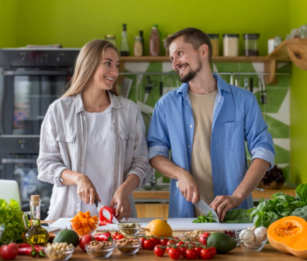 istock Attractive young couple cooking vegetable salad together in kitchen 1221327599