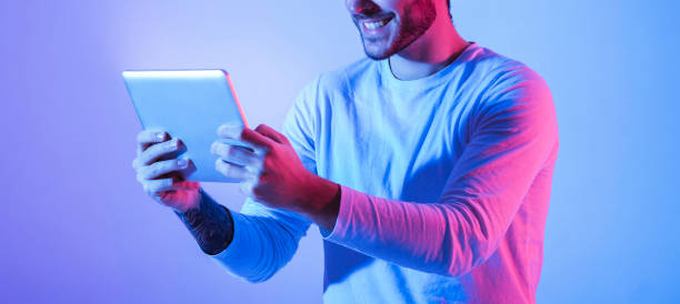 istock Man in neon with tablet in hands 1221328283