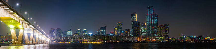 The skyscrapers of Yeouido glittering in the neon night of downtown Seoul across the Han River in the heart of South Korea’s vibrant capital city.